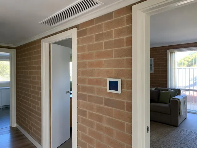 Ceiling ducted air outlet and wall controller in a brick hallway of a home in Paralowie